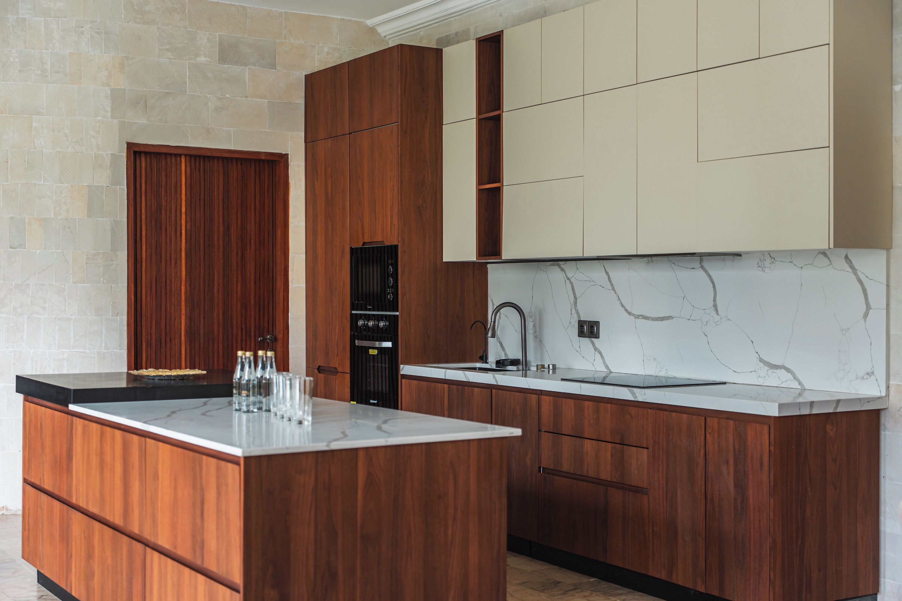 A modern kitchen with wooden cabinetry, a marble countertop, and a built-in oven.
