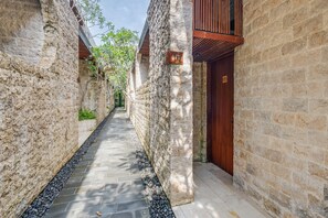 A narrow stone pathway flanked by buildings with wooden doors and a number sign. - ONYX Park Resort Ubud (Ubud)