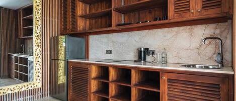 A kitchen with wooden cabinetry, marble countertop, and a stainless steel sink.