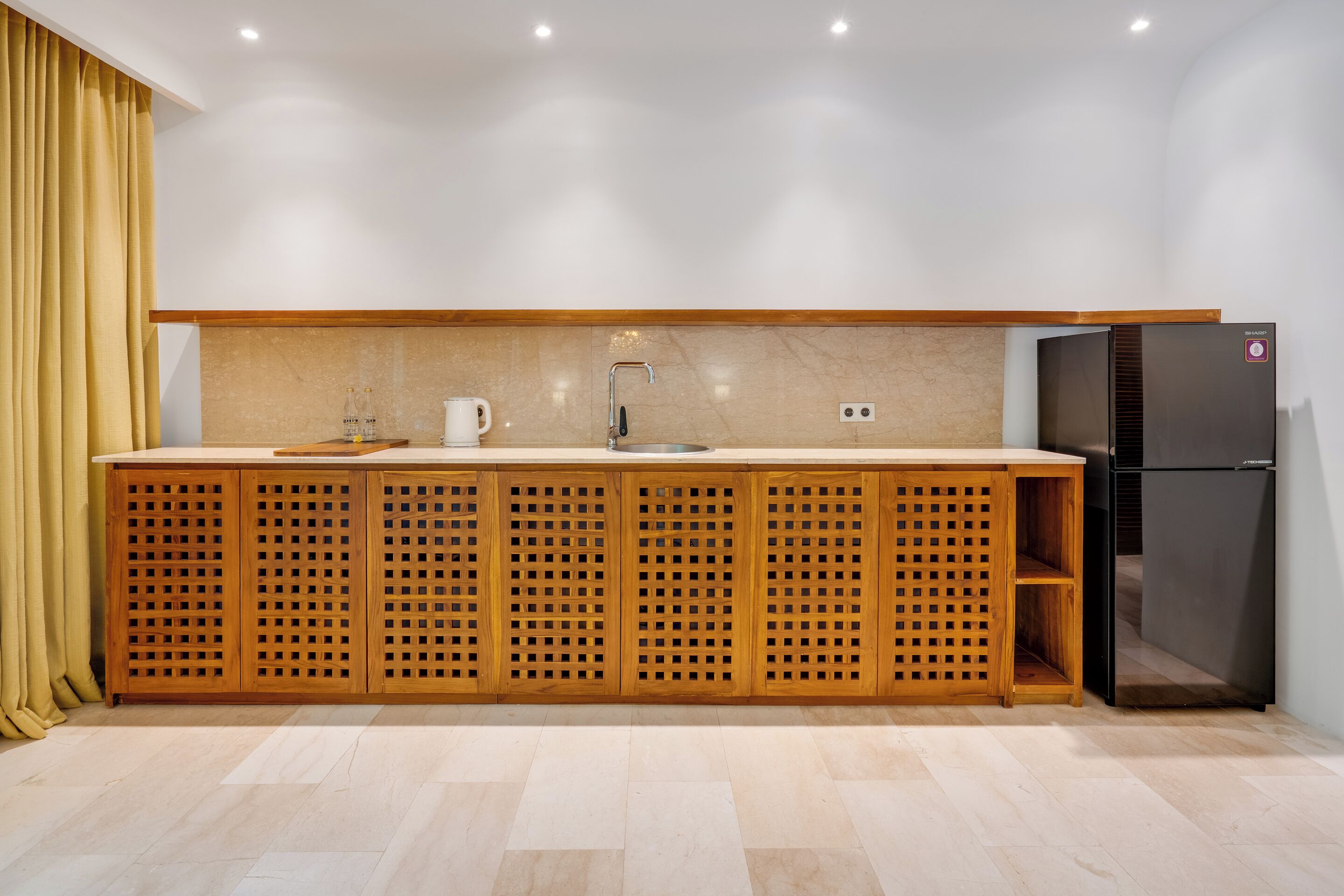 A modern kitchen with a wooden island, a built-in sink, and a black refrigerator.