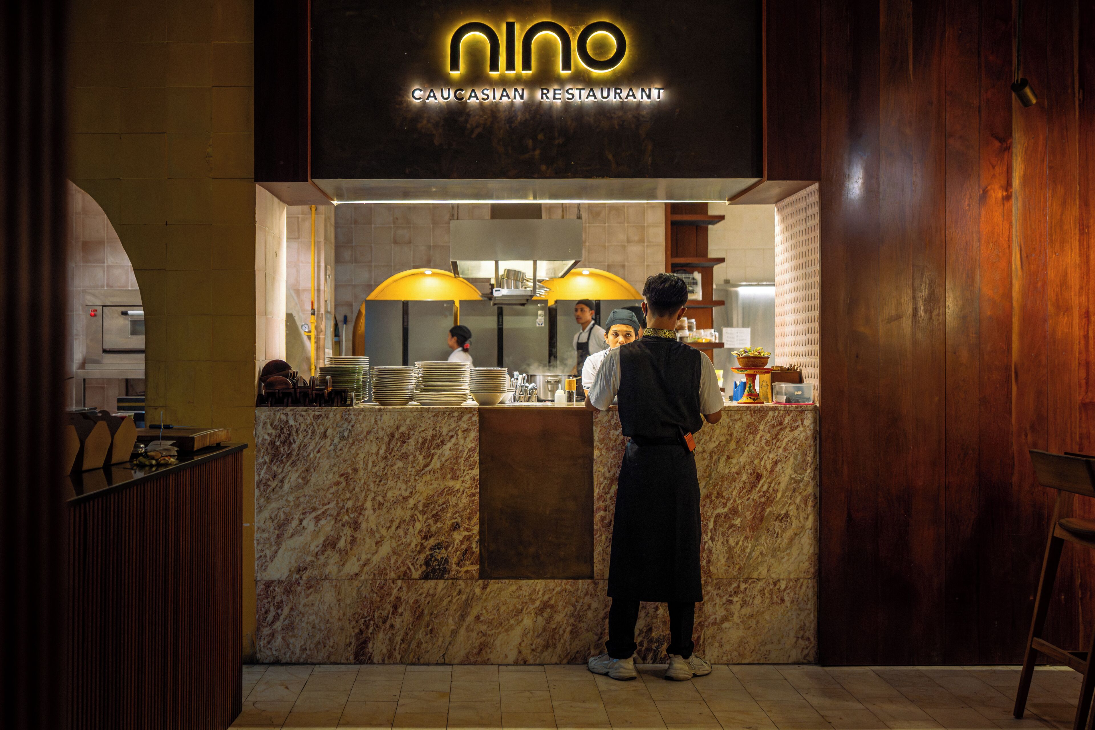 A restaurant with a marble counter and a sign that reads 'Nino Caucasian Restaurant'.
