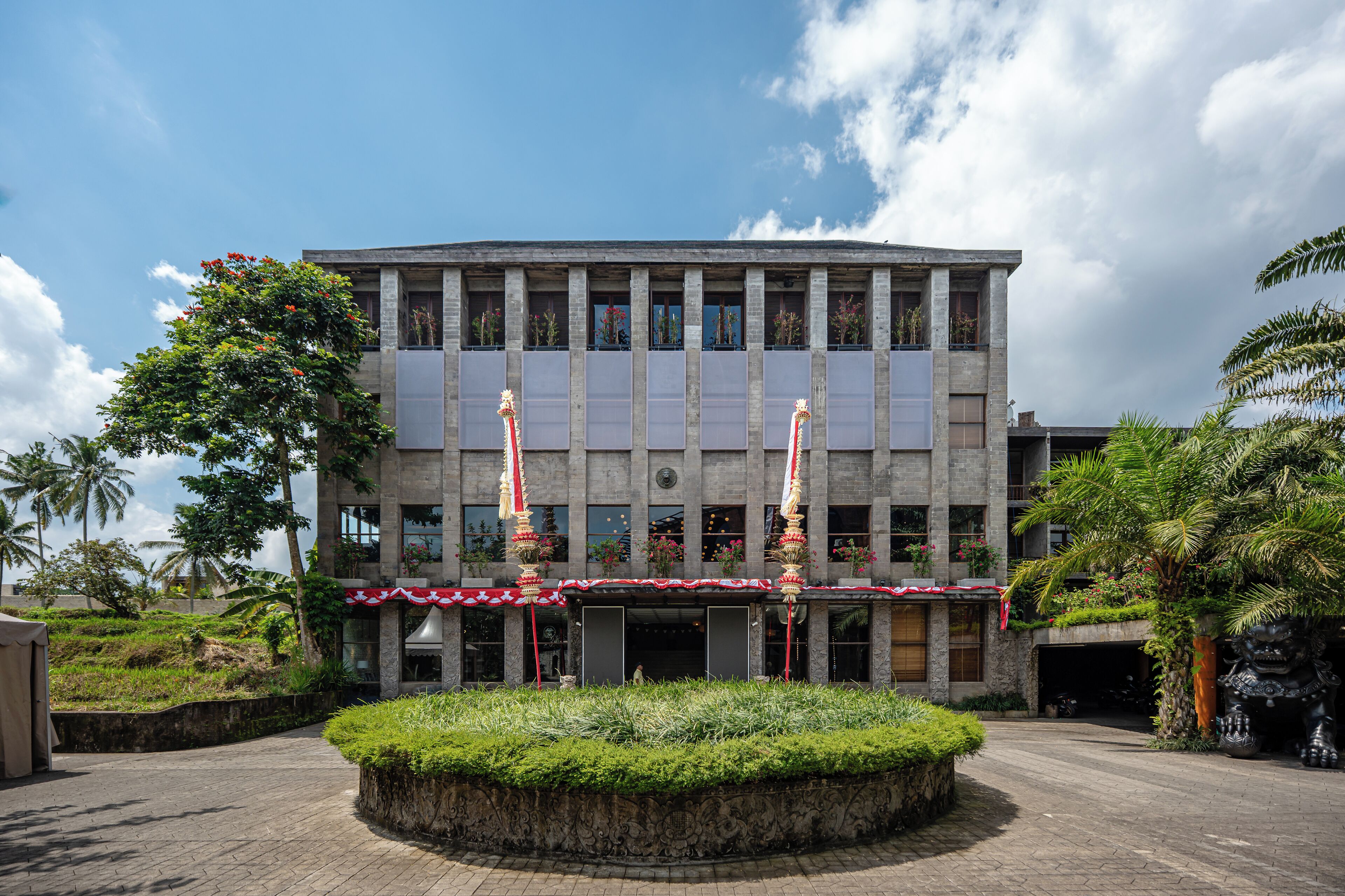 Un edificio moderno con un patio central, un acceso cubierto y una estatua.