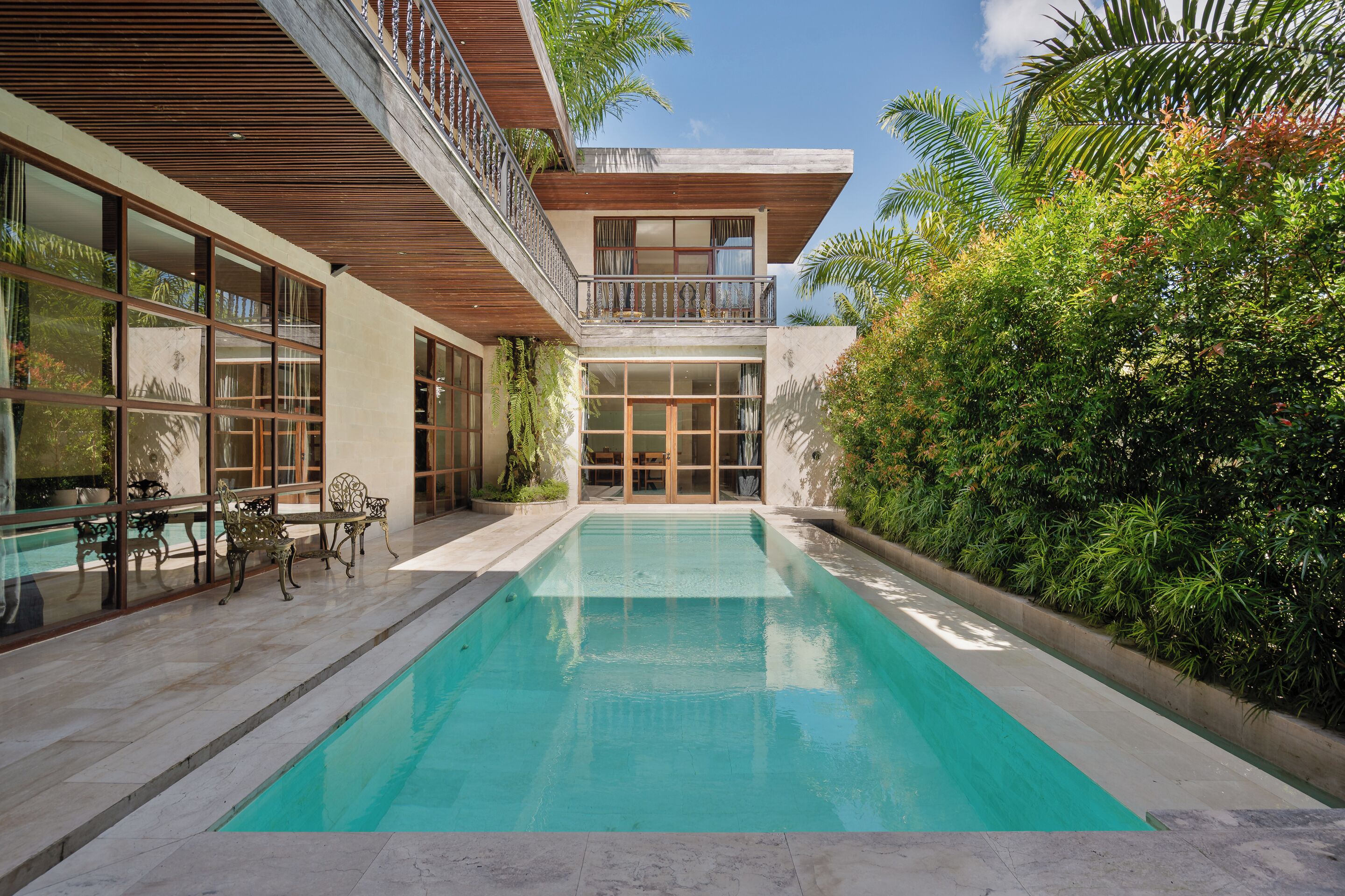 A modern house with a swimming pool, large windows, and a balcony.