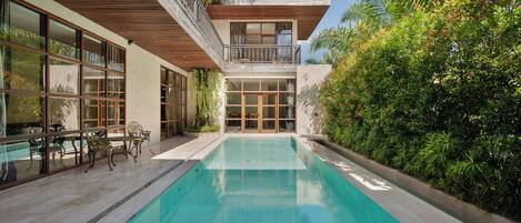 A modern house with a swimming pool, large windows, and a balcony.