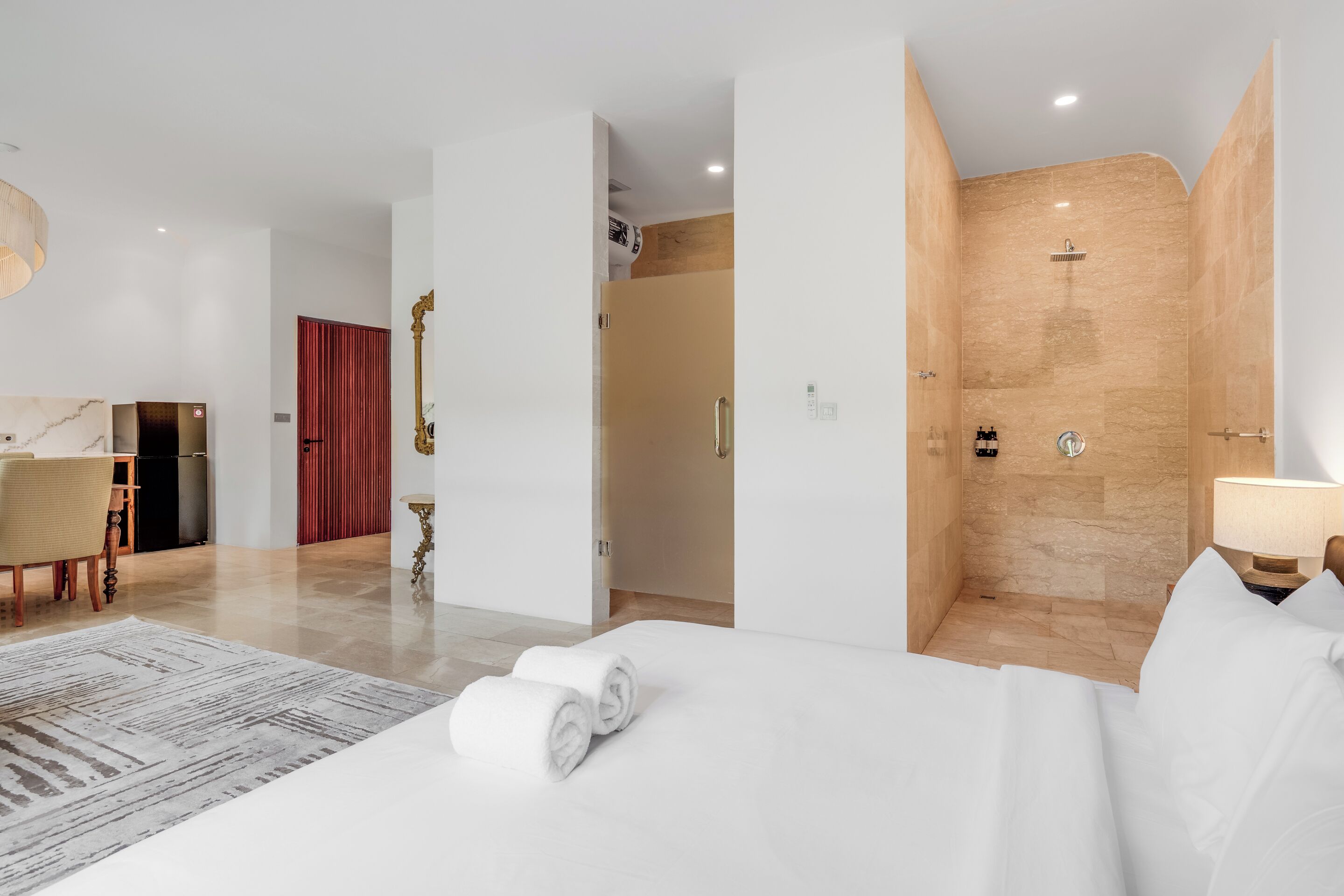 A hotel room with a bed, a desk, a shower, and a dining area.