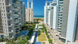 Un edificio residencial de gran altura con piscina, estacionamiento y vista a la playa.