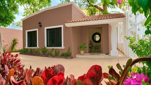 A two-story house with a beige exterior, a tiled roof, and a front porch. - La casa de los Alcatraces  (Cancún)