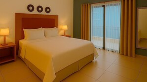 A hotel room with a large bed, two bedside tables with lamps, a ceiling fan, a balcony with curtains, and a large mirror on the wall. - La casa de los Alcatraces  (Cancún)