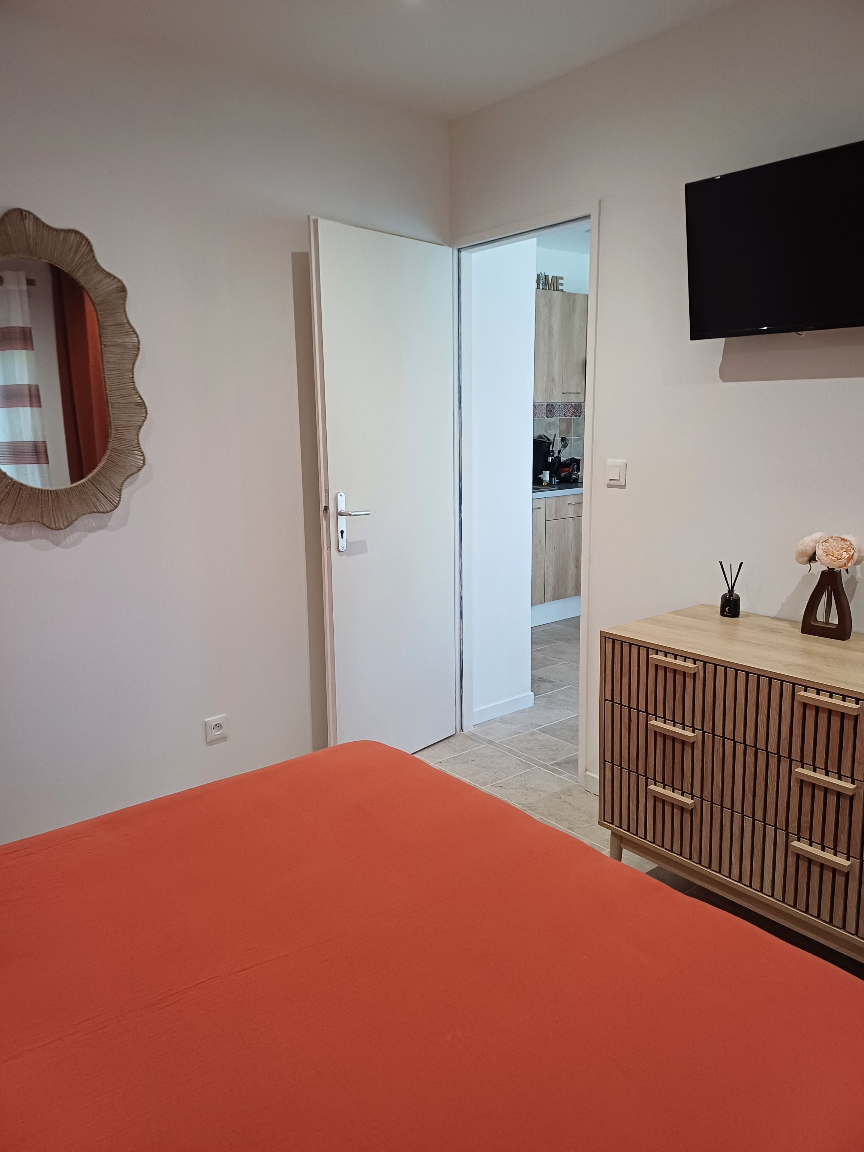 A bedroom with a bed, a wardrobe, a television, and a door leading to a bathroom.