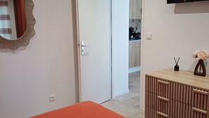 A bedroom with a bed, a wardrobe, a television, and a door leading to a bathroom. - Gîte Terre d'ocre (Hérépian)
