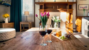 A wooden table with two wine glasses, a cheese platter, and a vase of flowers in a cozy room with a fireplace. - Sleeps 18 in 5 king, 1 king with bunk, 1 twin and 1 bunk room (Kincraig)
