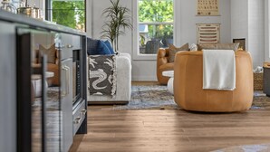 Una sala de estar moderna con un sofá, un sillón y un amplio ventanal con vistas a la vegetación.