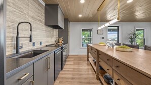 Cocina moderna con encimera de madera, electrodomésticos de acero inoxidable y un amplio ventanal que proporciona luz natural.