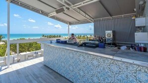 Um bar à beira-mar com vista para o oceano, balcão revestido de azulejos e mesas ao ar livre.