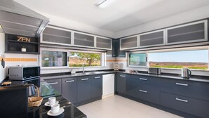 Une cuisine moderne avec des meubles de couleur sombre, un four à micro-ondes, un grille-pain et une vue sur l’extérieur.
