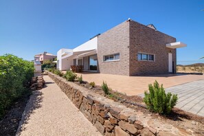 A modern house with a stone pathway, a patio, and a clear blue sky.