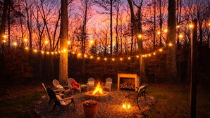 A cozy outdoor seating area with Adirondack chairs, a fire pit, and string lights. - Spacious 4BR Near Lake Allatoona Game Room Fire Pit 2 King Beds (Acworth)