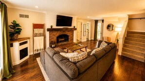 A living room with a fireplace, a sofa, a coffee table, and a TV. - Spacious 4BR Near Lake Allatoona Game Room Fire Pit 2 King Beds (Acworth)