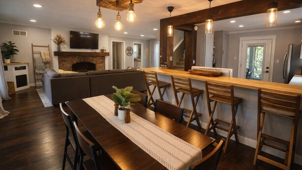 A modern kitchen with a wooden bar, a dining area with a table and chairs, and a built-in fireplace. - Spacious 4BR Near Lake Allatoona Game Room Fire Pit 2 King Beds (Acworth)