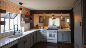 A modern kitchen with white cabinets, a built-in oven, and a large island. - Spacious 4BR Near Lake Allatoona Game Room Fire Pit 2 King Beds (Acworth)