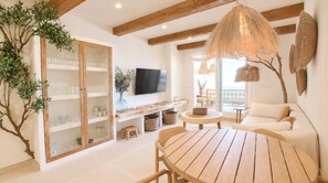 A modern living room with a wooden table, a sofa, a TV, and a large plant. - Residencial Marina Azul Beachfront (Denia)
