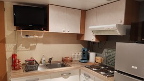 Uma cozinha compacta com micro-ondas integrado, cafeteira e geladeira.