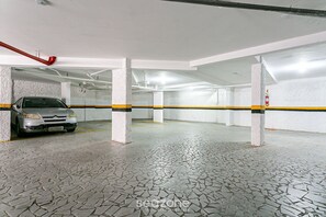 A parking garage with a tiled floor and a car parked in one of the spaces.