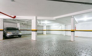A parking garage with a tiled floor and a car parked in one of the spaces.