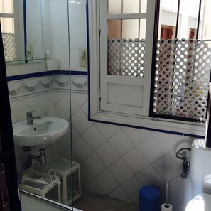 Un baño con lavamanos, espejo y ventana.
