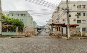 Uma rua pavimentada com um portão que dá acesso a um edifício de fachada de pedra e telhado de telhas vermelhas.
