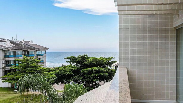 Un balcón con vista al mar, un edificio con paredes de azulejos y algo de vegetación.