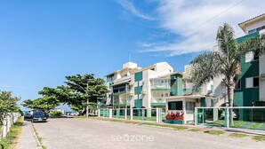 Un edificio residencial con varios balcones, entrada protegida y cielo despejado.