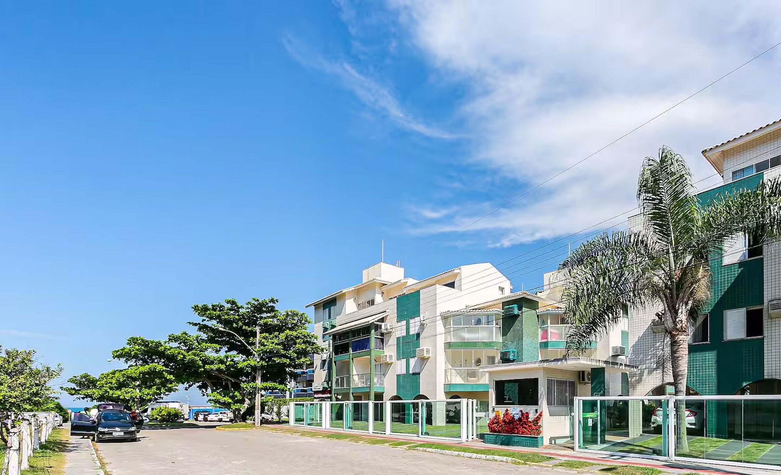 Un edificio residencial con varios balcones, entrada protegida y cielo despejado.