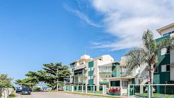 Un edificio residencial con varios balcones, entrada protegida y cielo despejado.
