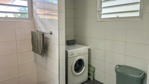Ett tvättrum med en tvättmaskin, ett torkställ och en tvättkorg.