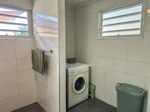 Ein Waschraum mit Waschmaschine, Wäscheständer und Wäschekorb.