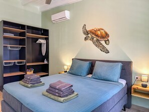 Een slaapkamer met een bed, een kledingkast, een wandairconditioner en een muurstickervel van een zeeschildpad.