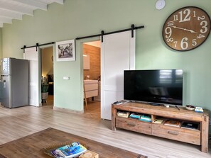 A modern living room with a flat-screen TV, wooden entertainment unit, and a large wall clock.