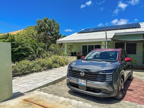 Ein schwarzer Nissan SUV parkt vor einem Haus mit grüner Dachbegrünung und der Hausnummer 45.