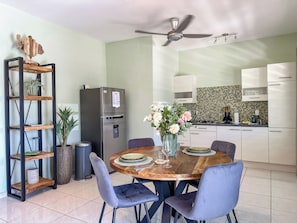 Een moderne keuken met een inbouwkoelkast, een eettafel met stoelen en een plafondventilator.