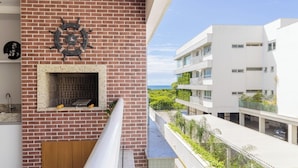 A modern apartment with a brick wall, a decorative ship's wheel, and a view of a building across a street. - Comfort Close to Campeche Beach! - Ddl0206 (Florianópolis)
