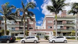 A multi-story residential building with balconies, a gated entrance, and parked cars. - Comfort Close to Campeche Beach! - Ddl0206 (Florianópolis)