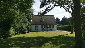 Ett hus med ett sluttande tak, en veranda och en liten trädgård.