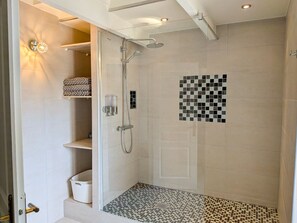 A walk-in shower with a glass door, tiled walls, and a checkered floor pattern.
