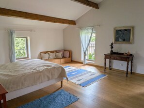 A bedroom with a bed, a sofa, a desk, and a window.