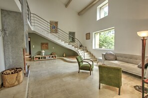 Ein geräumiger Wohnbereich mit einer geschwungenen Treppe, einem Sofa, einem Sessel und einer Lampe.