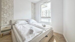 Een moderne slaapkamer met een groot raam, een nachtkastje en een ingebouwde bank.