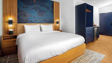 A modern hotel room with a large bed, wooden headboard, and a map mural on the wall.