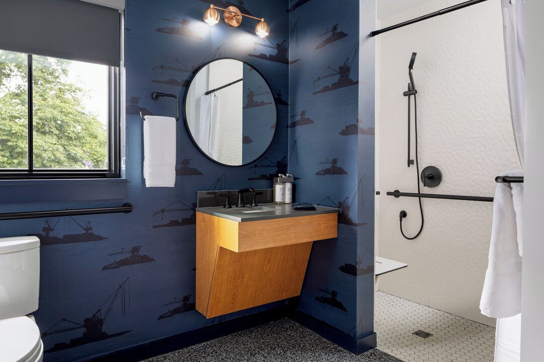Un baño con tocador de madera, espejo redondo, inodoro y ducha.