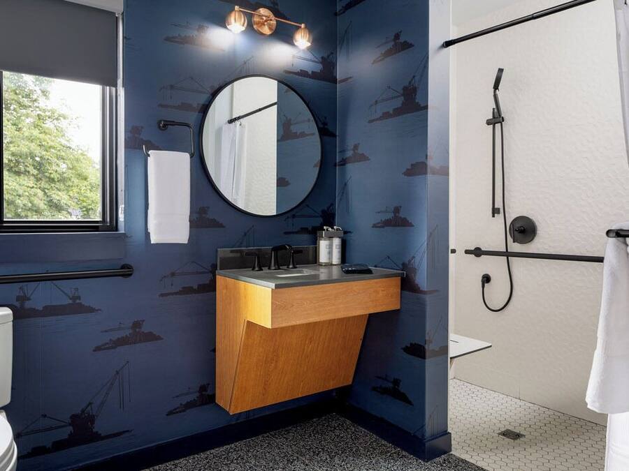 Un baño con tocador de madera, espejo redondo, inodoro y ducha.